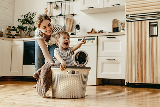 Happy family mother housewife and child in laundry with washing machine